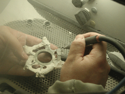 Der Rohguss hergestellt mit Cast von Ti-Research wird im Sandstrahlgerät von Einbettmasseresten befreit